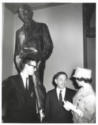 ["Black and white photograph of Carl Albert and unidentified people under a statue of Will Rogers."]