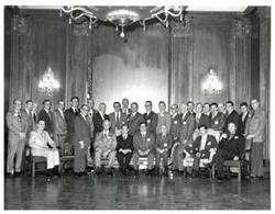 ["Black and white photograph of Carl Albert with a group of unidentified men. Not pictured: a handwritten note from Carl Albert, (to unaddressed) from Carl's Speaker's desk, stating, \"he thought (unaddressed) would be interested in this\" (Carl Albert)."]