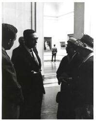 ["Black and white photograph of Carl Albert with unidentified people, in the foyer of a gallery."]