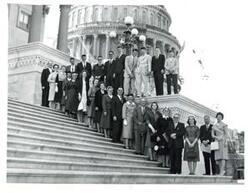 ["Black and white photograph of a group of people standing on capitol steps."]