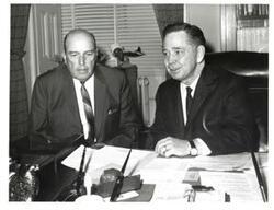 ["Black and white photograph of Carl Albert sitting behind a desk with another man. Note: there is an unpictured typed note, from the office of Carl Albert, ordering a couple photos be sent to the President (Robert E. Goldfield) and Secretary (Terry R. Hill) of the Delta Beta Chapter of the Alpha Phi Omega National Service Fraternity included with the photograph."]
