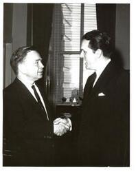 ["Black and white photograph of Carl Albert shaking hands with a man in an office."]
