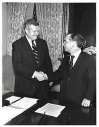 ["Black and white photograph of Carl Albert shaking hands with a man in an office."]