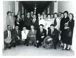 ["Black and white photograph of Carl Albert with a group in a hallway."]