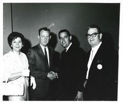 ["Black and white photograph of Three unidentified people and Fred Harris."]
