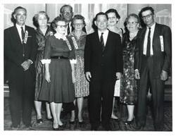 ["Black and white photograph of from left: Joe Gilder, Mrs. Paul Kelton, Anna Belle Lofever, Paul Kelton, Francis Newport, Carl Albert Mrs. Dayton Burnside, Mrs. Joe Elder, and Dayton Burnside."]