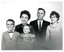 ["Black and white photograph of Carl Albert with the Otis Thomas family. 1962. Handwritten note on back of photograph (not pictured), Otis Thomas' Mother-In-Law, identifying family and family members in photograph."]