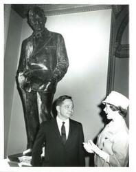 ["Black and white photograph of Carl Albert standing under a Will Rogers statue with a member of the joint committee on children and youth."]