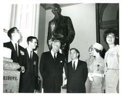 ["Black and white photograph of Carl Albert with group under Will Rogers statue."]