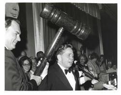 ["Black and white photograph of Carl Albert receiving a giant honorary gavel."]