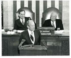 ["Black and white photograph of  Gerald R. Ford speaking at a joint session of Congress. Carl Albert and James O. Eastland also shown. October 8, 1974"]