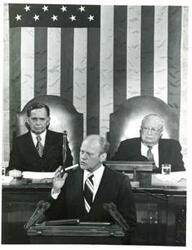 ["Black and white photograph of  Gerald R. Ford speaking at a joint session of Congress. Carl Albert and James O. Eastland also shown. October 8, 1974"]