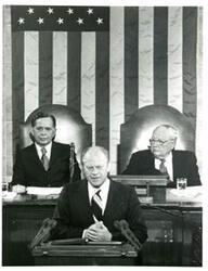 ["Black and white photograph of  Gerald R. Ford speaking at a joint session of Congress. Carl Albert and James O. Eastland also shown. October 8, 1974"]