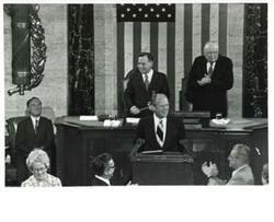 ["Black and white photograph of  Gerald R. Ford speaking at a joint session of Congress. Carl Albert and James O. Eastland also shown. October 8, 1974"]