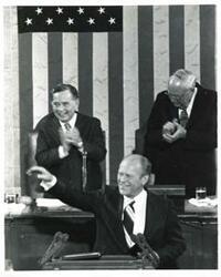 ["Black and white photograph of  Gerald R. Ford speaking at a joint session of Congress. Carl Albert and James O. Eastland also shown. October 8, 1974"]