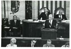 ["Black and white photograph of  Gerald R. Ford speaking at a joint session of Congress. Carl Albert and James O. Eastland also shown. October 8, 1974"]