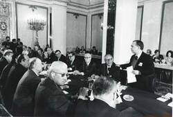 ["Black and white photograph print of Carl Albert, Robert Michel, Melvin Price, Clement Zablocki, Edward Boland, John Brademas, Millicent Fenwick, and several others seated at a conference table during the House delegation trip to USSR, Romania, Yugoslavia. August 1975"]