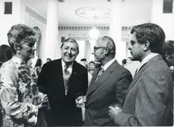 ["Black and white photograph print of Robert Michel speaking with unidentified men and a woman. House delegation trip. August 1975"]