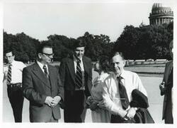 ["Black and white photograph print of Carl Albert and Mary Albert standing outside with several people. House delegation trip. August 1975"]