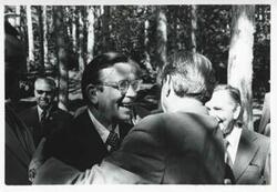 ["Black and white photograph print of Carl Albert, Edward Boland, and other men standing outside. House delegation trip. August 1975"]