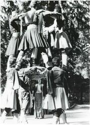 ["Black and white photograph print of a group of people performing a dance during the House delegation trip. August 1975"]