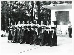 ["Black and white photograph print of a group of people performing a dance during the House delegation trip. August 1975"]