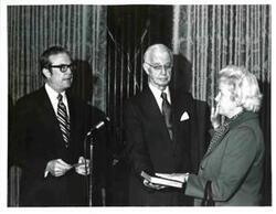 ["Black and white photograph of  Woman being sworn in, taking an oath."]