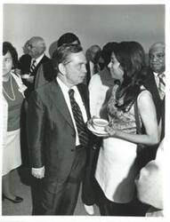 ["Carl Albert talking to a woman in a crowded room."]