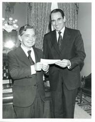 ["Carl Albert and another man holding a check."]