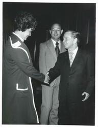 ["Carl Albert shaking hands with a woman."]