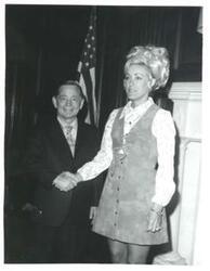 ["Carl Albert shaking hands with a woman."]