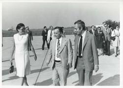 ["Black and white photograph print of Carl Albert with several other people walking outside at an airport."]