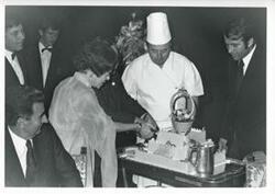 ["Black and white photograph print of Carl Albert and Mary Albert at an unidentified function. They are cutting a cake (similar to #382)."]