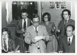 ["Black and white photograph print of Carl Albert standing with several unidentified people."]