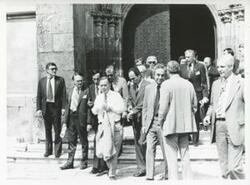 ["Black and white photograph print of Carl Albert walking outside a building with several other people. House delegation trip. August 1975"]