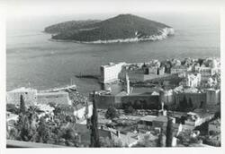 ["Black and white photograph print of an aerial view of a city, body of water, and an island."]