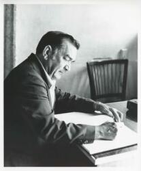 ["Black and white photograph print of Cement Zablocki working at his desk."]