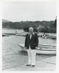 ["Black and white photograph print of James Quillen standing on a dock. Several boats are in the background."]