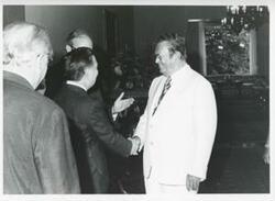 ["Black and white photograph print of President Josip B. Tito of Yugoslavia shaking hands with Carl Albert as others look on."]