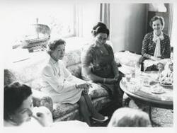 ["Black and white photograph print of Mary Albert seated on a couch with other women. House delegation trip. August 1975"]