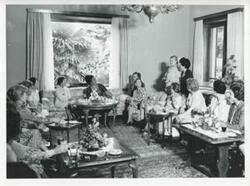 ["Black and white photograph print of Mary Albert seated on a couch with other women. House delegation trip. August 1975"]
