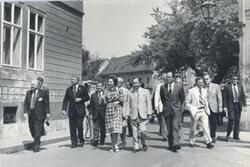 ["Black and white photograph print of Carl Albert walking down the street with several people."]
