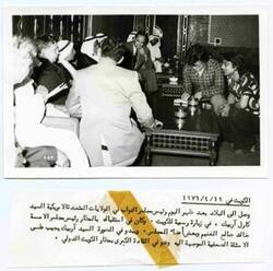 ["Carl Albert with the Interior President of Kuwait National Assembly Khalid al-Ghuniam on the left of Albert on the couch with many unknown men looking on"]