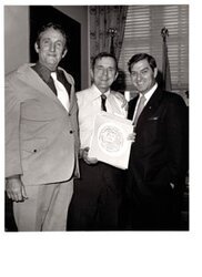 ["The image depicts Dewey Bartlett standing with Harold (Tex) Brown and another gentleman"]