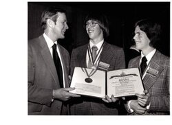 ["The image depicts Dewey Bartlett presenting Mike Pierret and Blake Dutcher with a certificate of scholarship"]