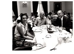 ["The image depicts Dewey Bartlett seated at a dinner table with Eillen and Ray Mortimer"]