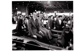 ["The image depicts Dewey Bartlett seated in the back of a car with Richard Nixon"]