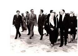 ["The image depicts Dewey Bartlett walking across a runway with Fawaz Kudsi, Strang, Phillip Griffen, Faraj Hamoudah, Paul Fannin, Ann Bartlett, and several others"]