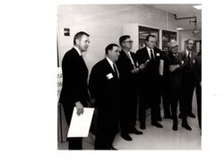 ["The image depicts Dewey Bartlett standing with several other men"]