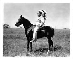 ["LaDonna Harris (foreground) with Fred R. Harris seated behind a desk There is a photo and campaign sign for Hubert H Humphrey While the foreground of the image is clear the background is blurred"]